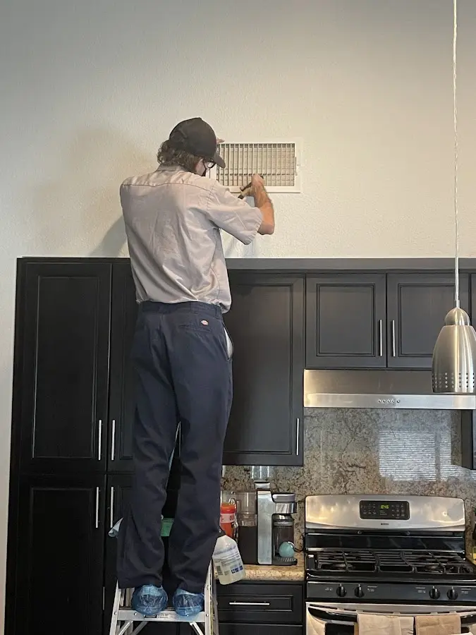 Technician inspecting an air vent during HVAC service in Howell